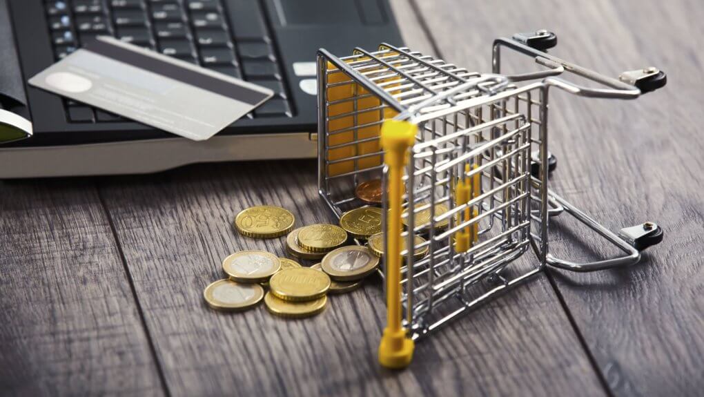 Abandoned Shopping Cart mini figure with coins next to open laptop