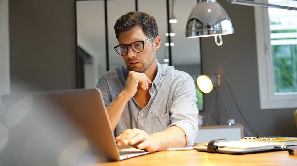 man looking at the opened laptop on a desk