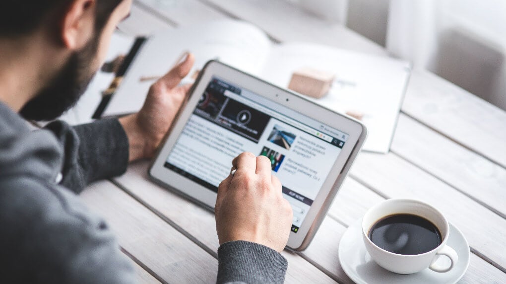 Men scrolling news on tablet