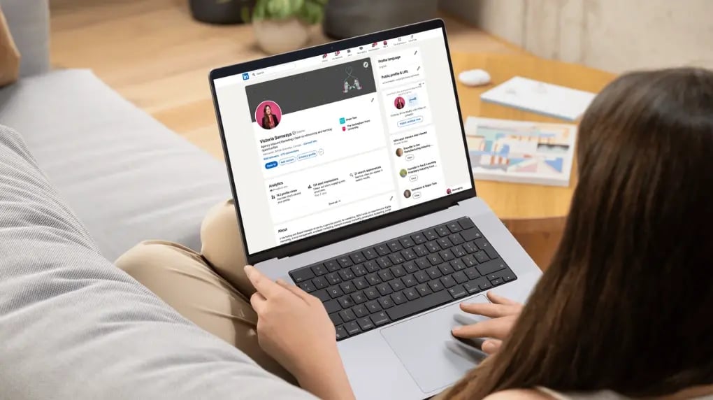 Women sitting on a couch using her laptop to update her LinkedIn profile.