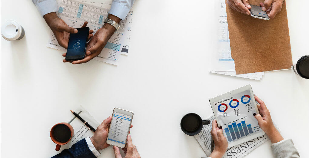 four people hands holding phones nad tablets