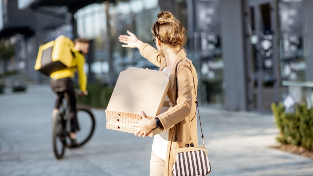 woman with pizza boxes waving at food delivery courier