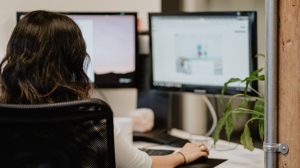 women working at desk with two computers